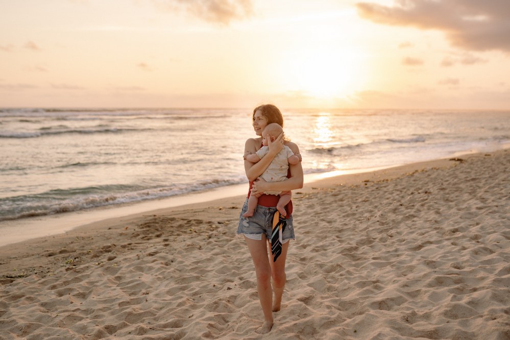 mum carrying infant on the beach