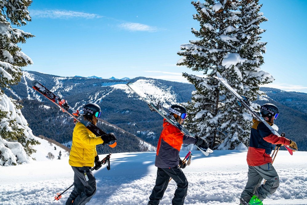 3 skiers carrying skis