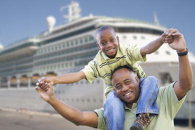 Stock image of father and son in front of a cruise ship