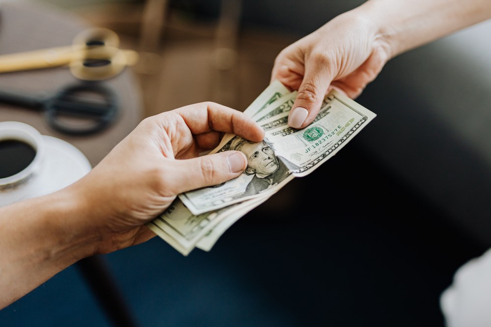 two hands holding same bank notes