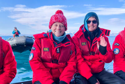 two people smiling while riding a zodiac boat in Svalbard