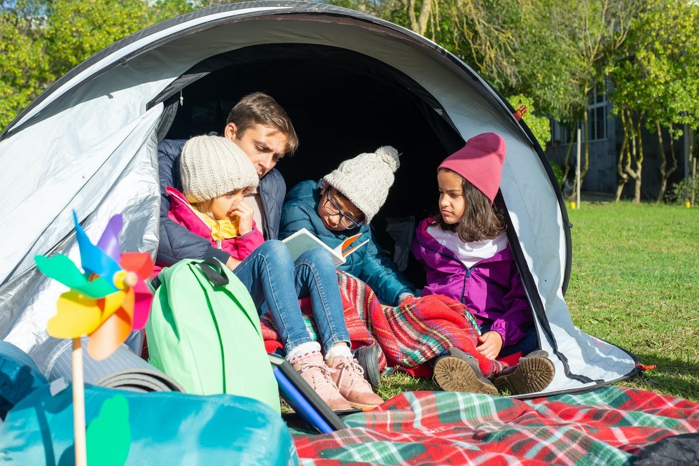 dad and children in tent on family camping holiday