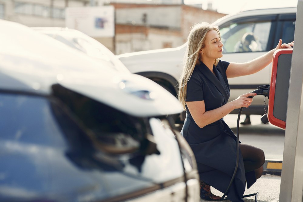 woman charging her electric vehicle at public charging point